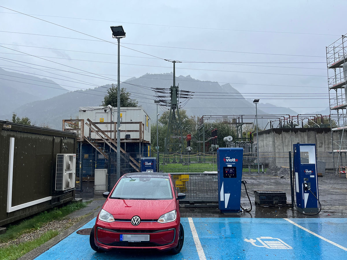 Zweiter Ladestopp in Österreich, "malerisch" gelegen vor einer Strominstallation, schon wieder ohne Regenschutz, aber immerhin mit Blick auf die Berge (was in Österreich quasi ohnehin unvermeidlich ist). Foto: itt